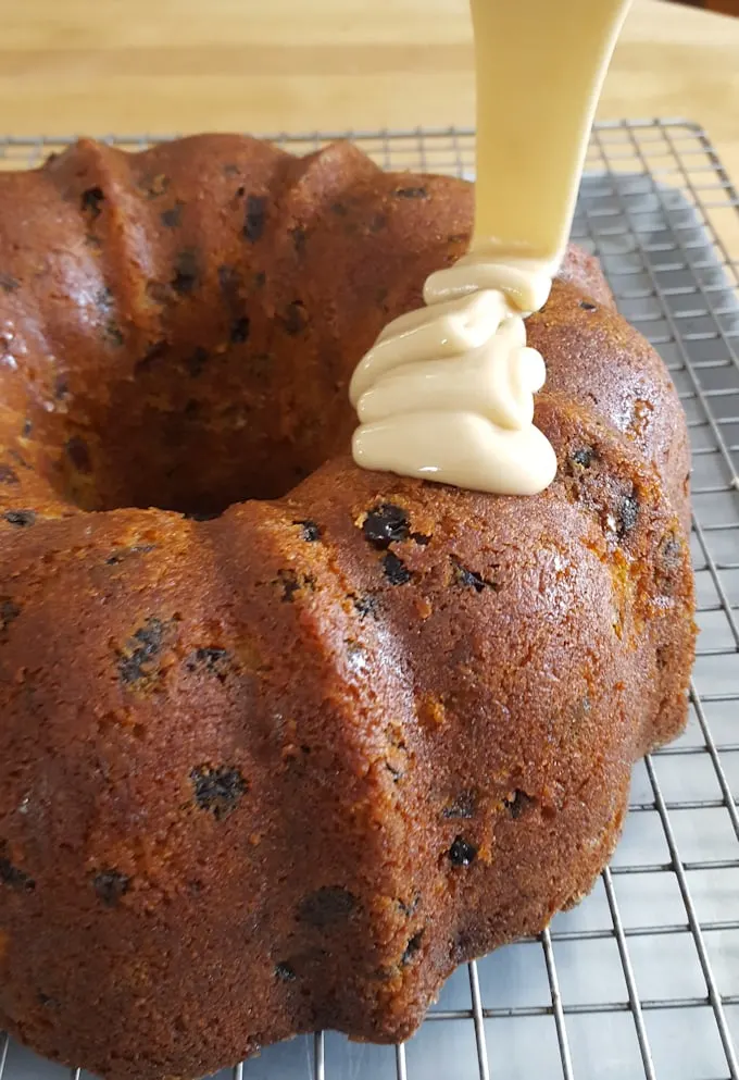 glaze being poured over a bundt cake on a cooling rack