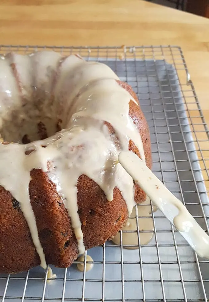 a spatula spreading glaze on a bundt cake