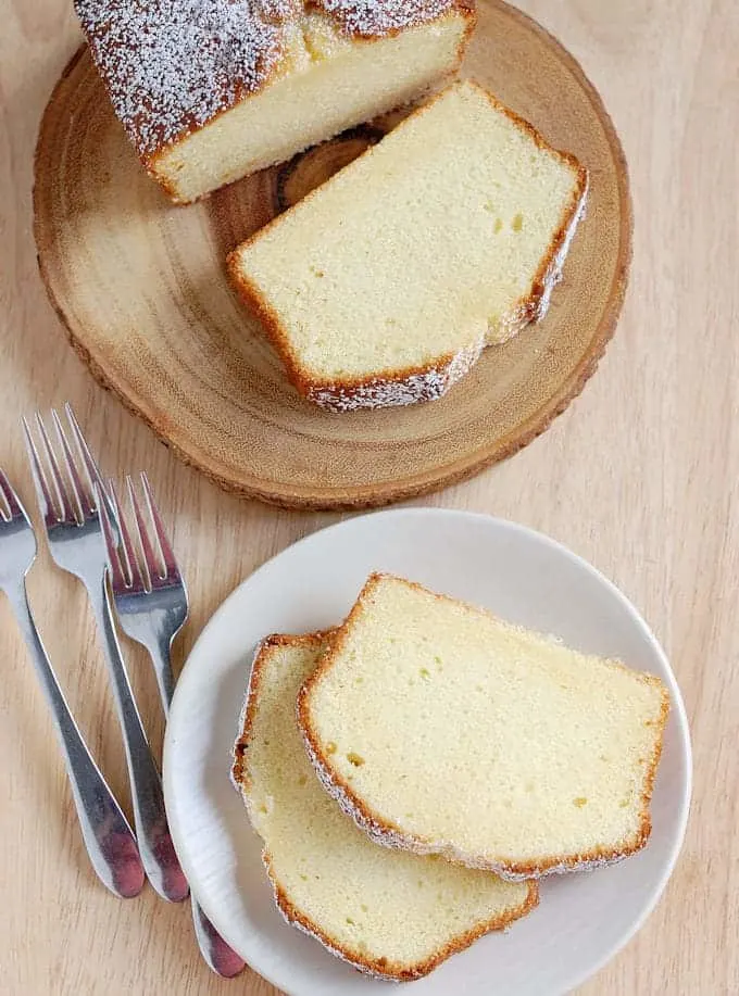 slices of Sour Cream Pound Cake on a plate and wooden cutting board