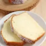 Two slices of cake on a white plate on a wood table. Blue text overlay says perfect pound cake