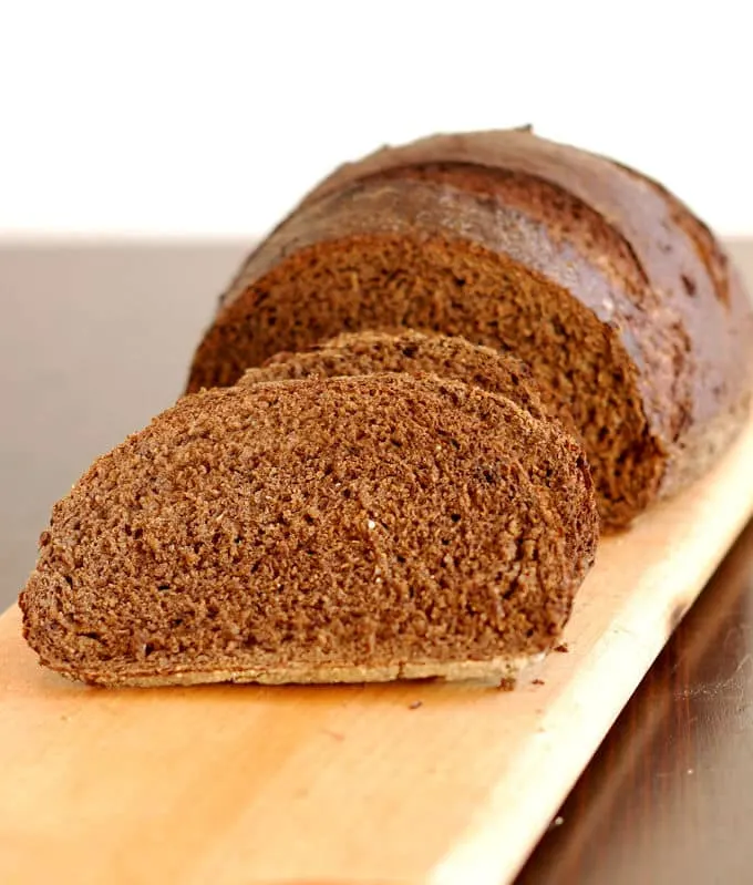 sliced loaf of sourdough pumpernickel bread on a cutting board