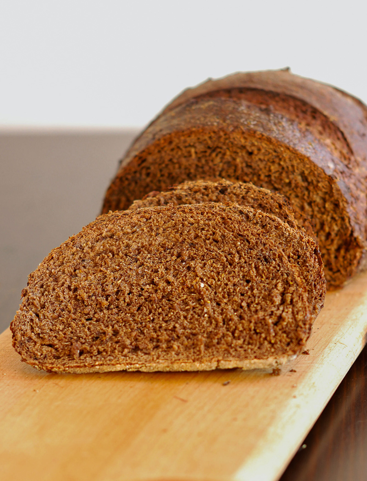 a sliced loaf of sourdough pumpernickel bread on a cutting board.