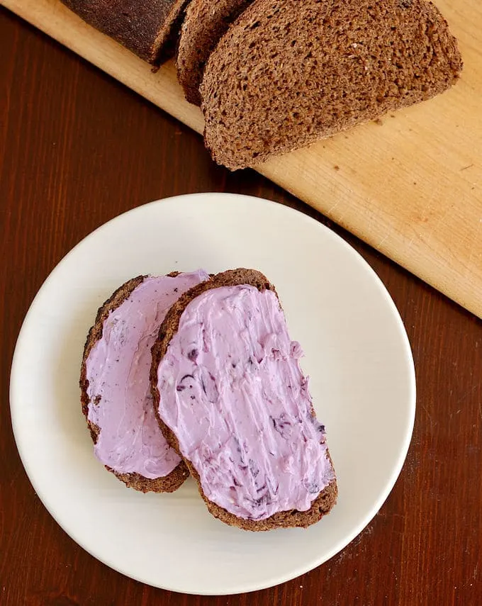 two slices of sourdough pumpernickel bread with blueberry cream cheese on a white plate