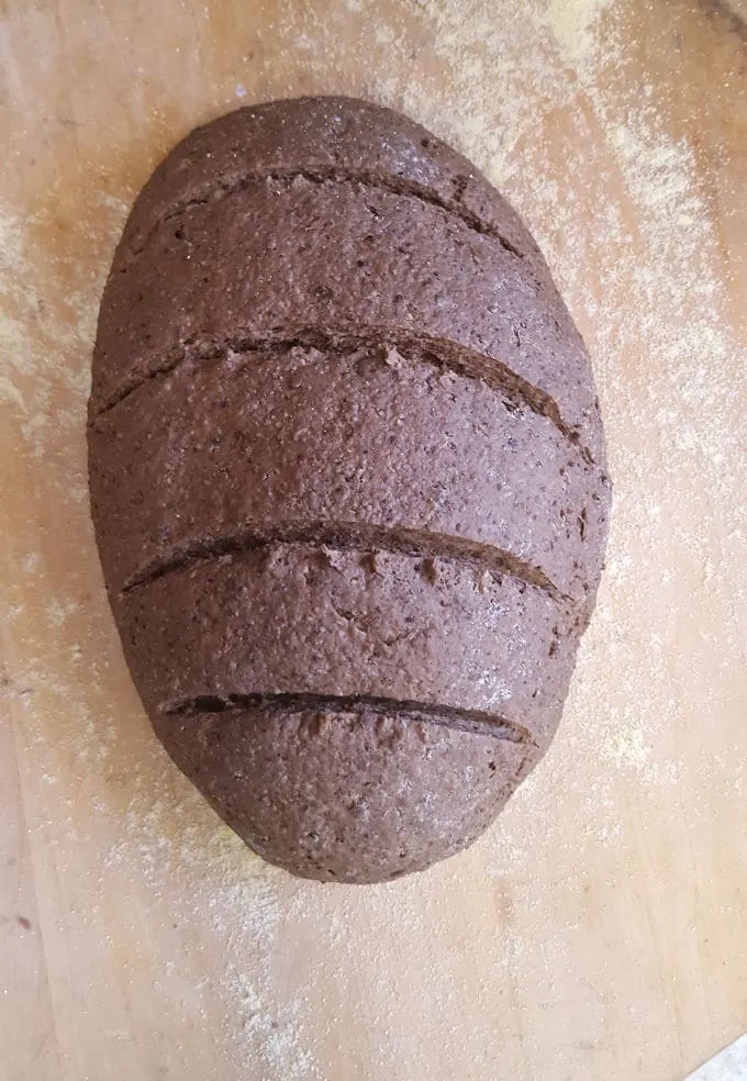 a loaf of dark brown pumpernickel bread ready for the oven