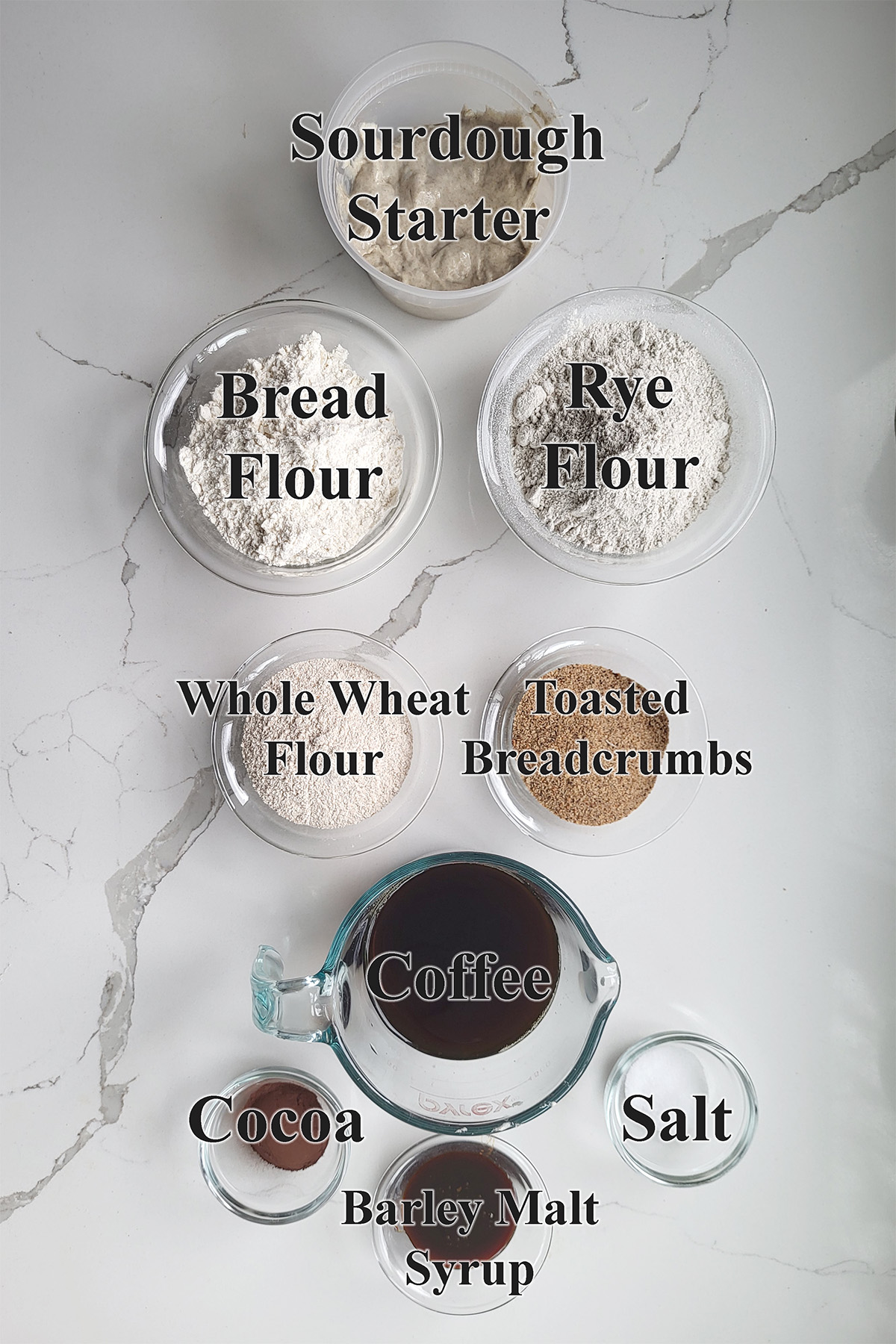 ingredients for sourdough pumpernickel bread in glass bowls.