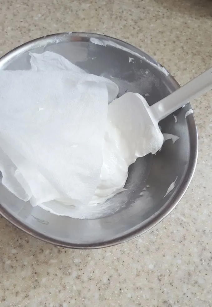 a bowl of royal icing covered with a damp towel