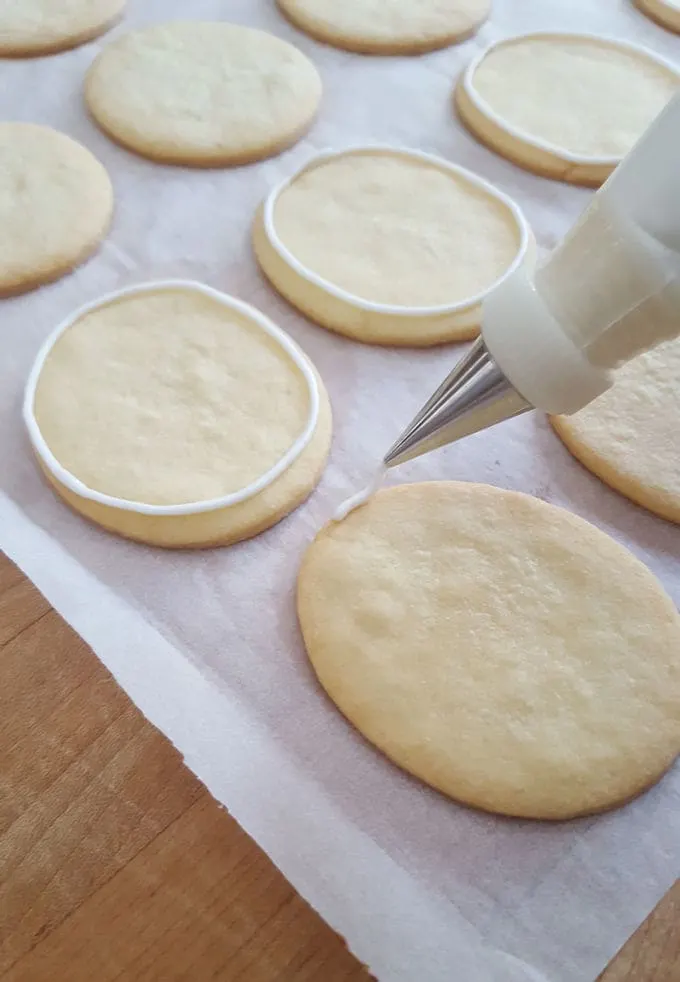 piping royal icing on a cookie
