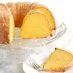 a slice of golden beet orange cake on a plate and the sliced cake on a glass cake stand