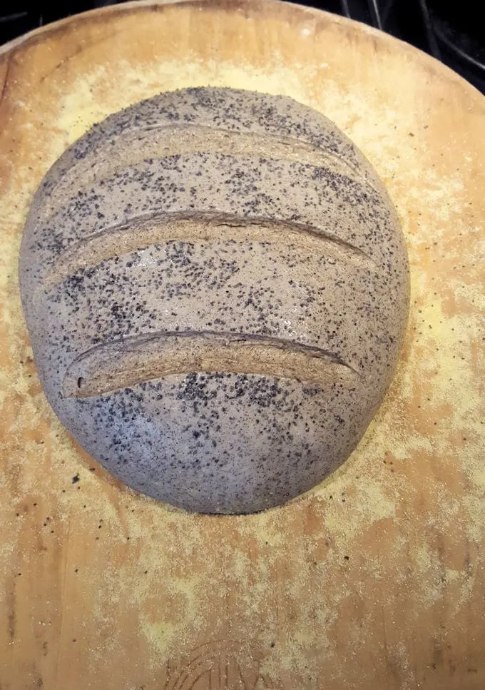 a loaf of unbaked guinness buckwheat bread on a wooden peel