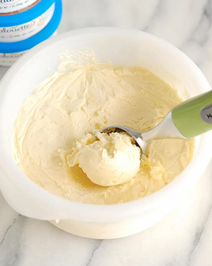 a container of creme fraiche ice cream with a scooper