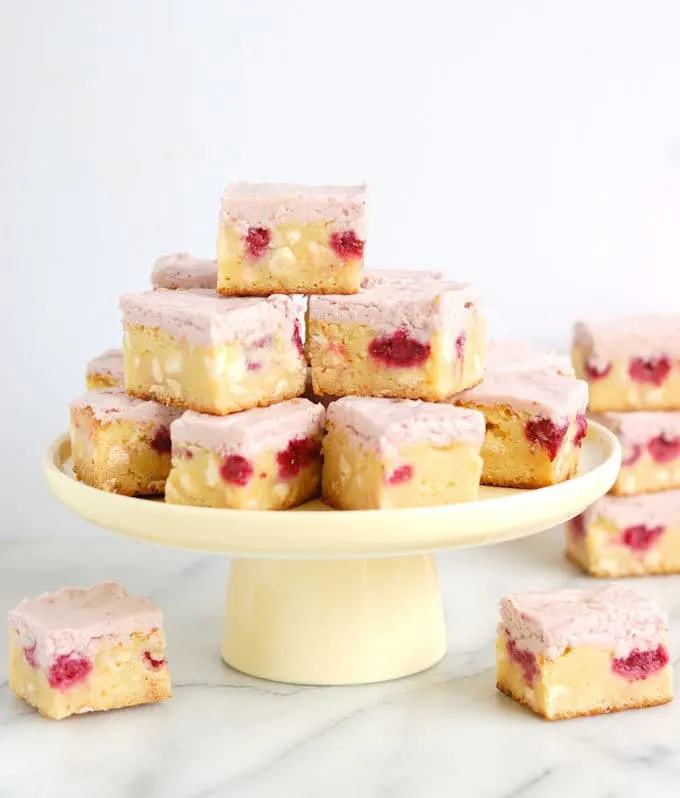 a tray of white chocolate brownies with raspberries and raspberry frosting