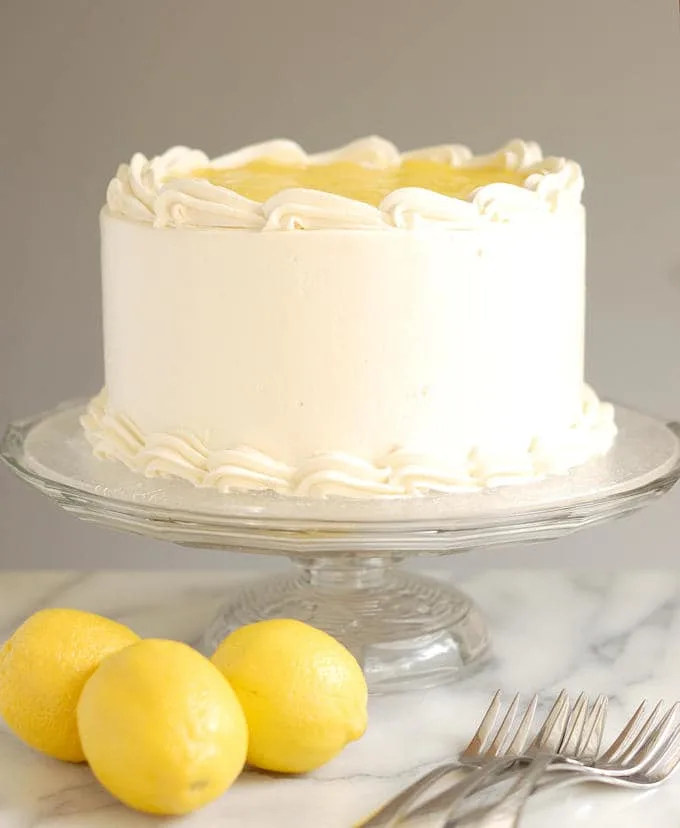 a lemon layer cake on a glass cake stand