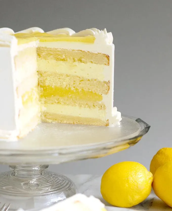 A lemon layer cake on a glass cake stand.