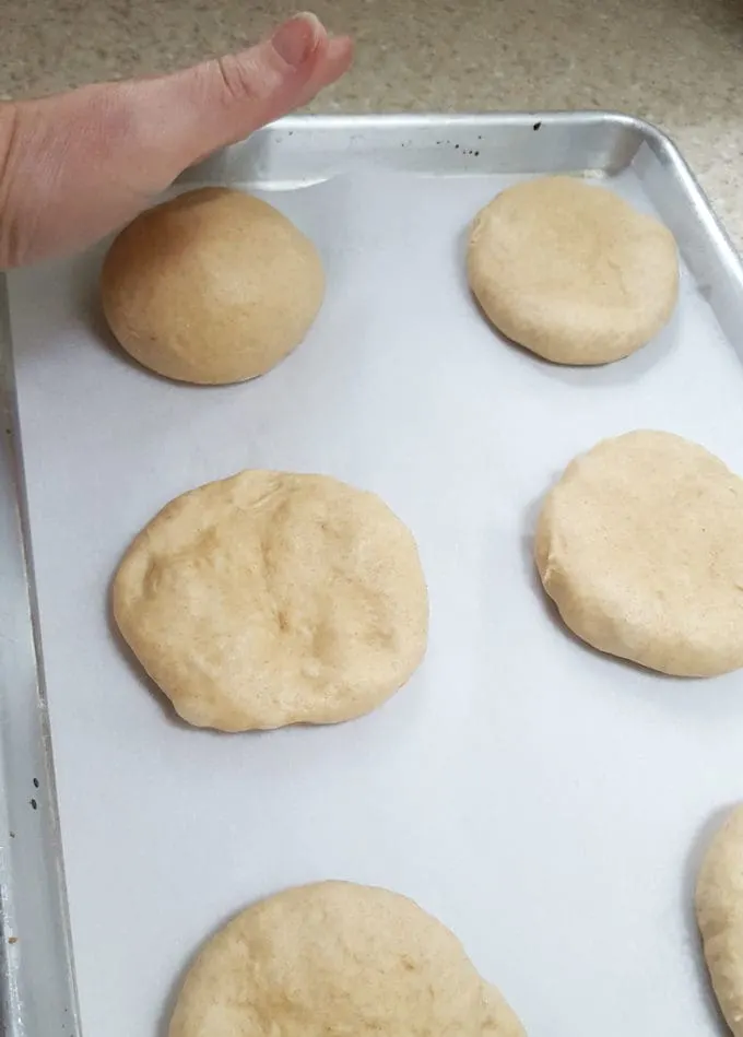 showing how to flatten dough for burger buns