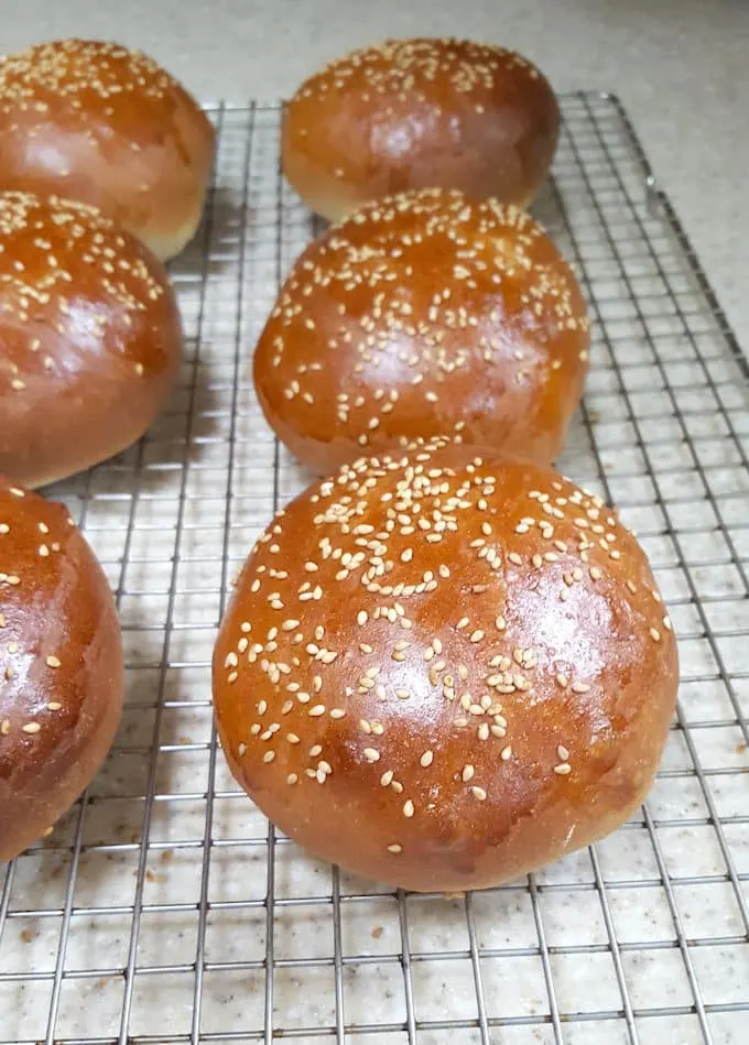 Golden brown whole wheat hamburger buns cooling on a rack