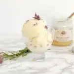 a glass dish with lavender honey ice cream and lavender blossoms