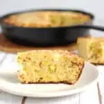 a slice of smoked cornbread with a cast iron skillet in background