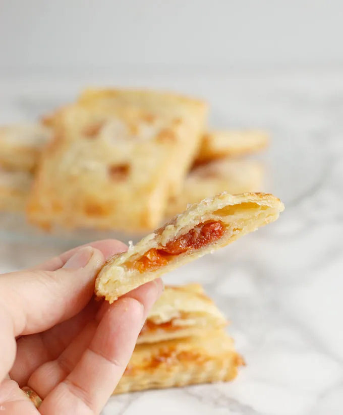 a hand holding a cherry almond hand pie