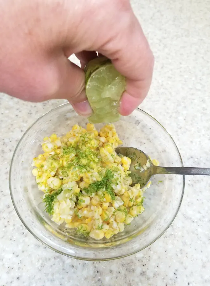 squeezing lime juice into fresh corn