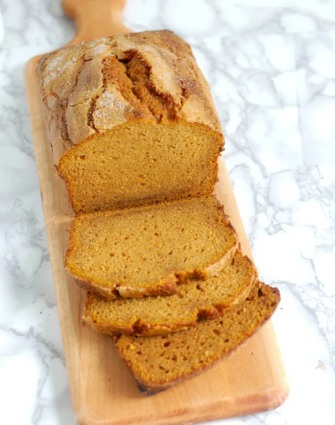 a sliced loaf of moist pumpkin bread on a cutting board