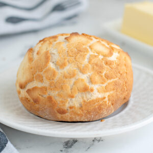 a dutch crunch roll on a white plate.