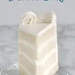 A slice of 4 layer white cake with white icing on a glass plate.