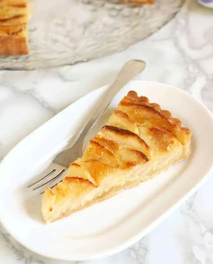 a slice of Apple Frangipane Tart on an oval plate with a fork