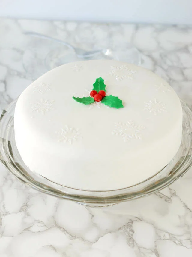 a white fruitcake on a glass stand.