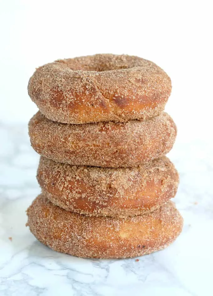 a stack of sourdough donuts with cinnamon sugar against a white background