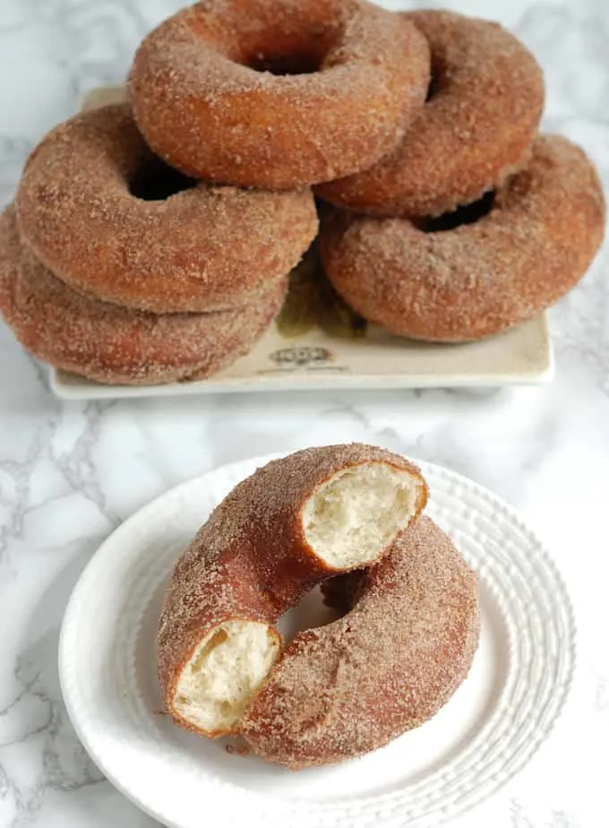a stack of cinnamon sugar donuts and one on a plate