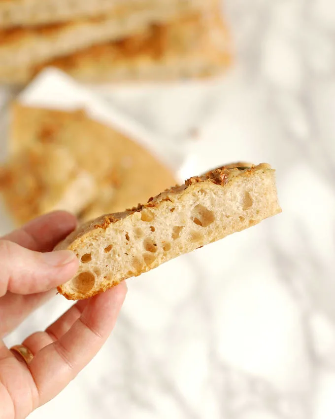 a hand holding a slice of sourdough focaccia