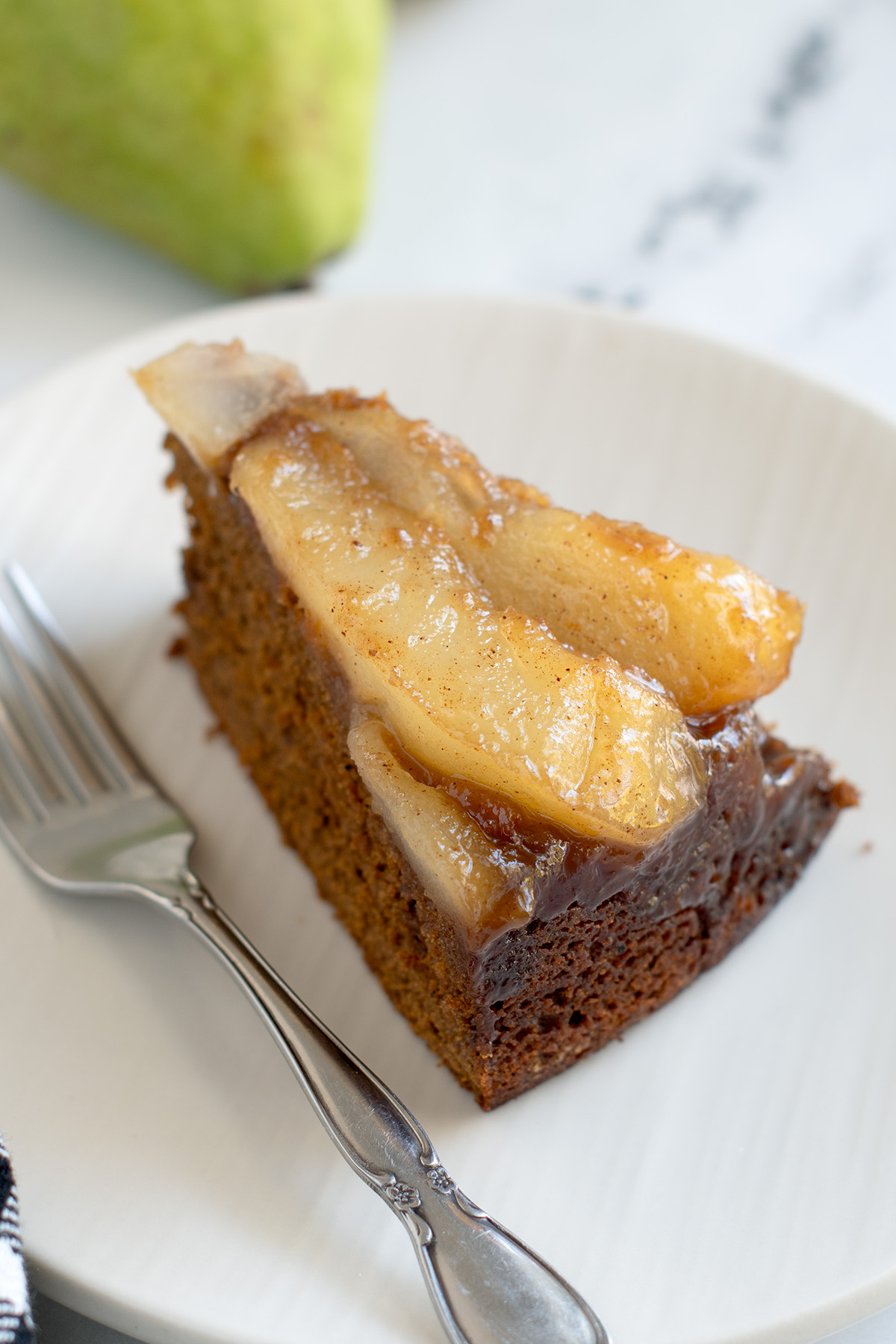 a SLICE OF pear gingerbread cake on a white plate.