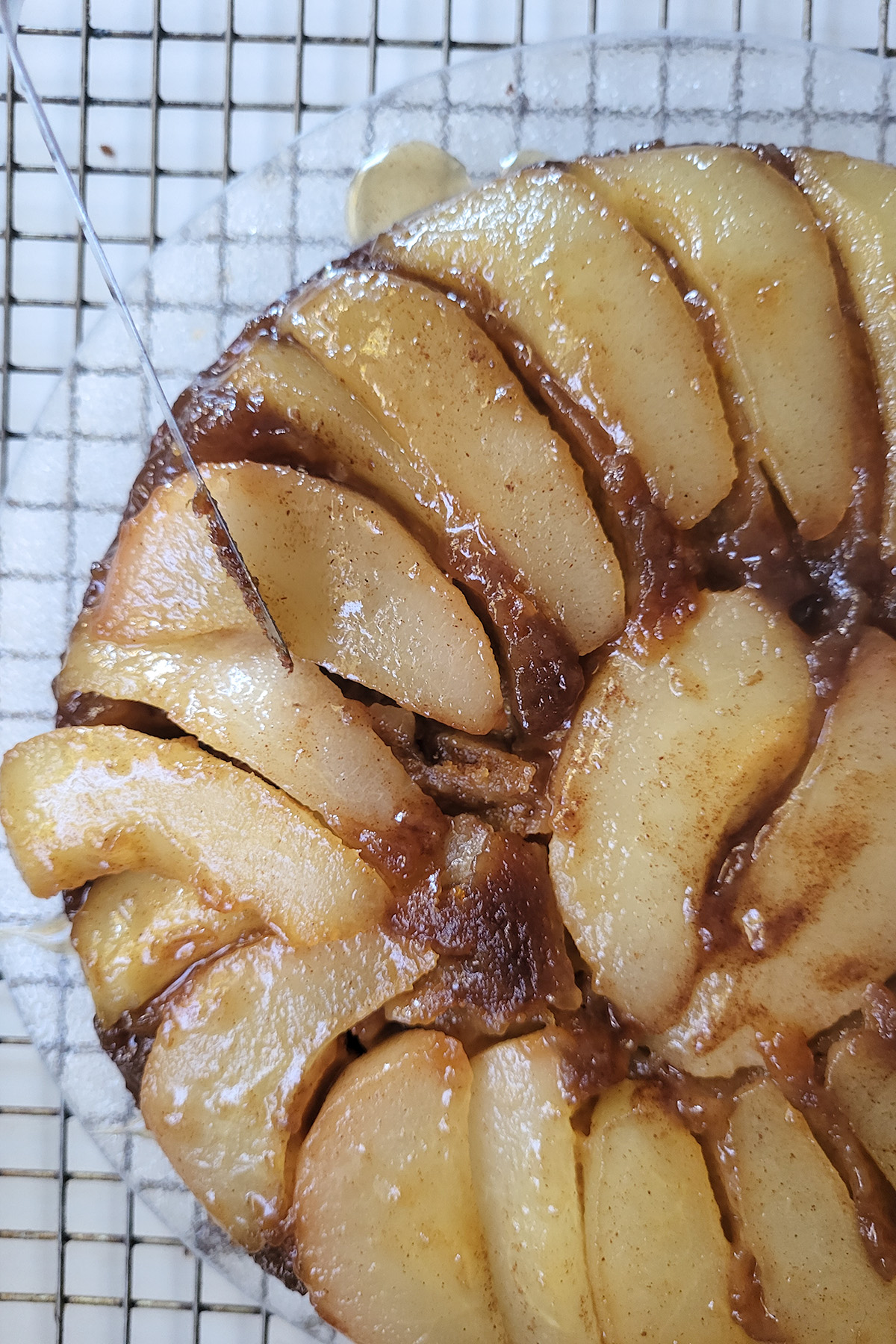 a closeup of a pear upside down ginger cake on a cooling rack.