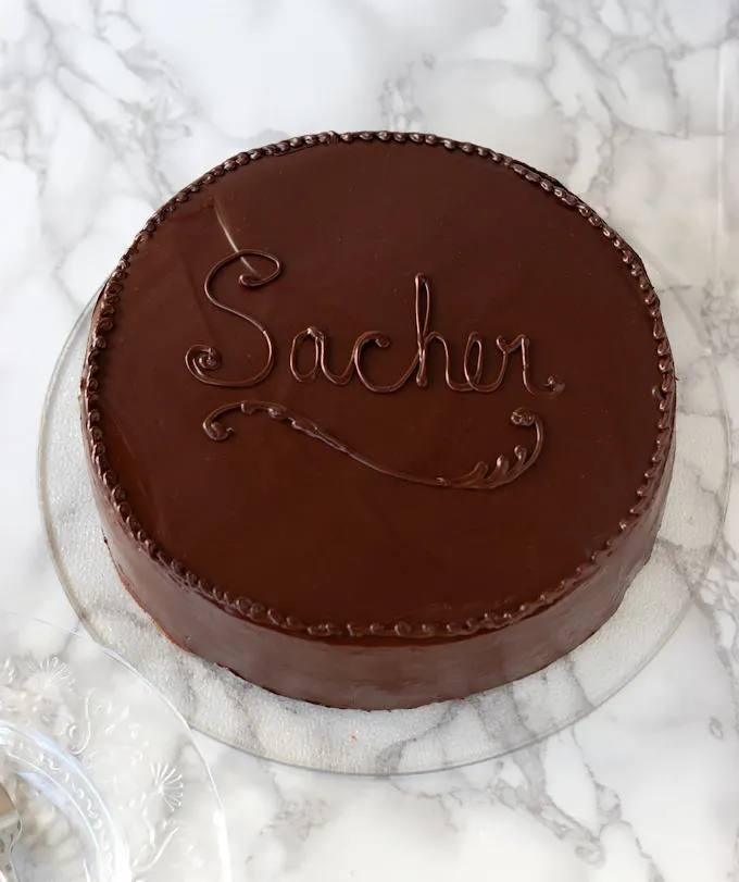 a sacher torte on a glass cake plate