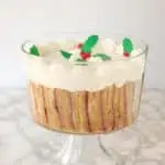 a sherry trifle in a footed glass bowl holly leaves and berry decoration