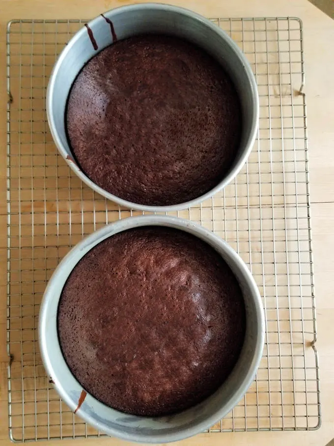 two chocolate cakes cooling on a rack.