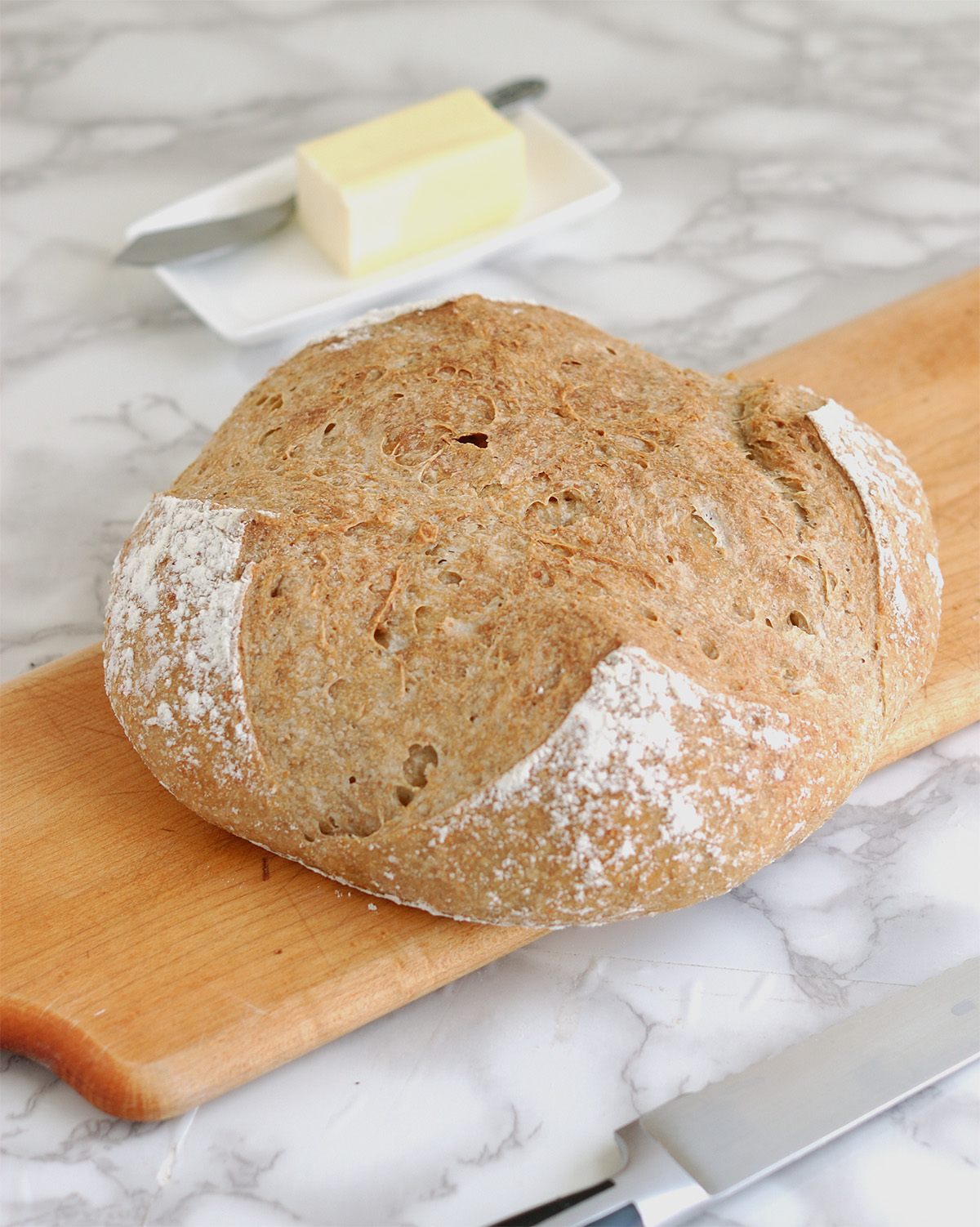 a loaf of whole grain low knead bread on a cutting board.