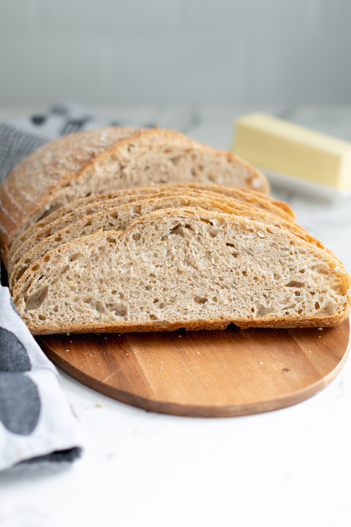 a sliced loaf of whole grain low knead bread on a cutting board.