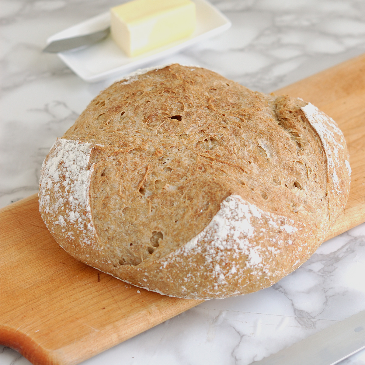 a loaf of whole grain low knead bread on a cutting board.