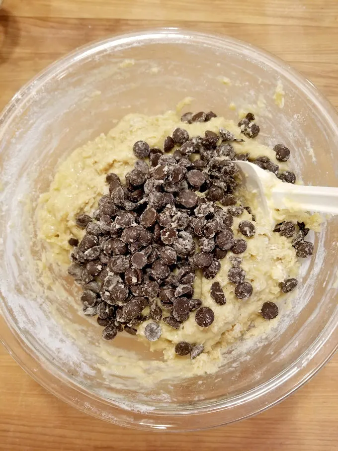 Folding chocolate chunks into banana bread batter.