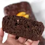 a hand holding a slice of chocolate orange zucchini bread