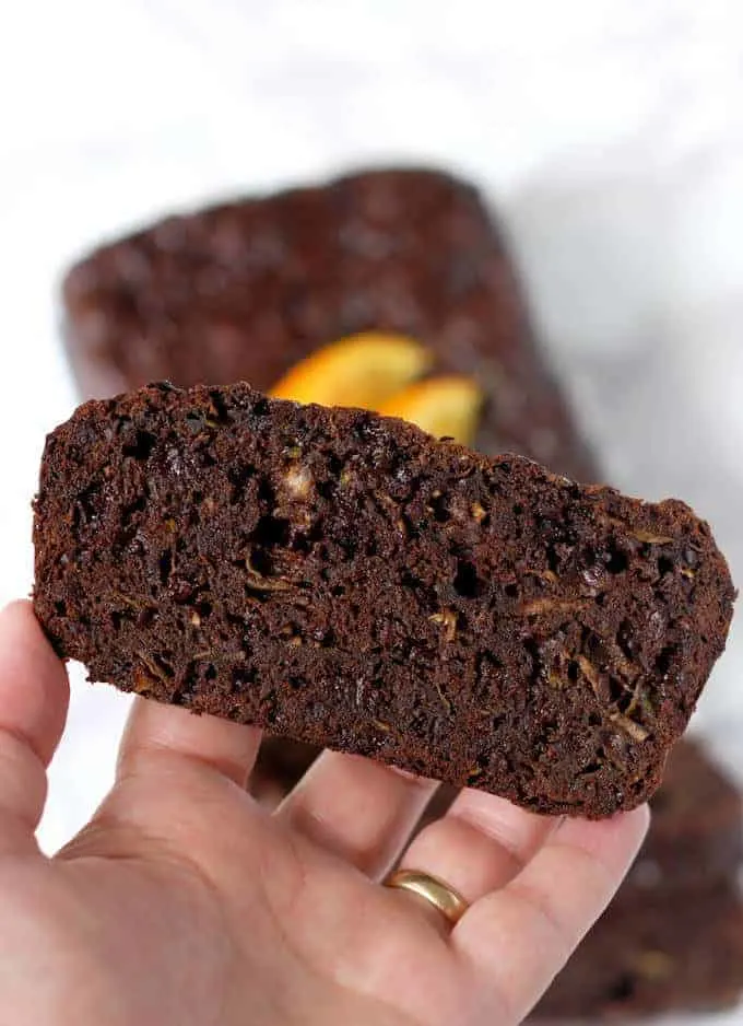 a hand holding a slice of chocolate orange zucchini bread