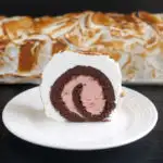a slice of strawberry baked alaska cake roll on a white plate