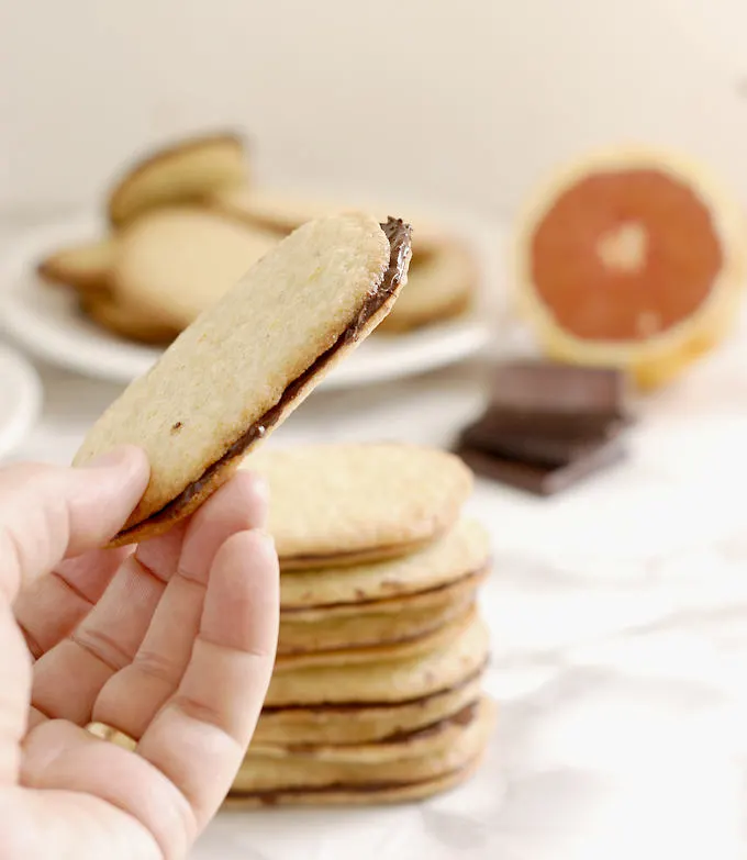 an Orange thin cookie with semi sweet chocolate filling