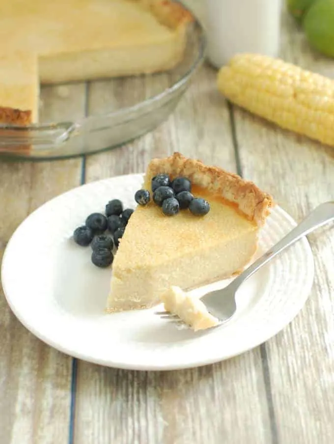 a slice of Sweet Corn Buttermilk Pie served with fresh blueberries