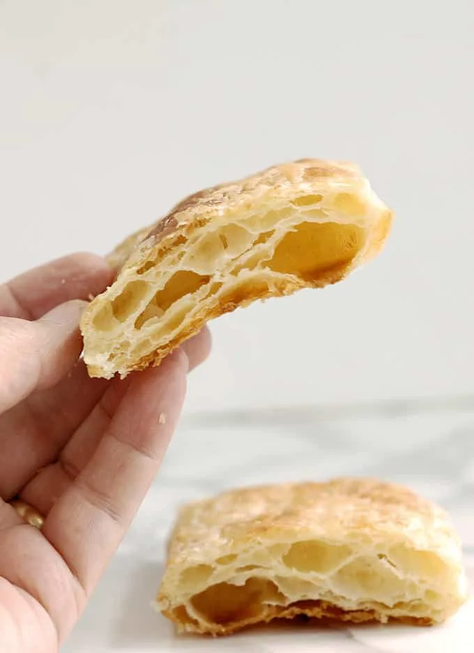 a hand holding a piece of puff pastry