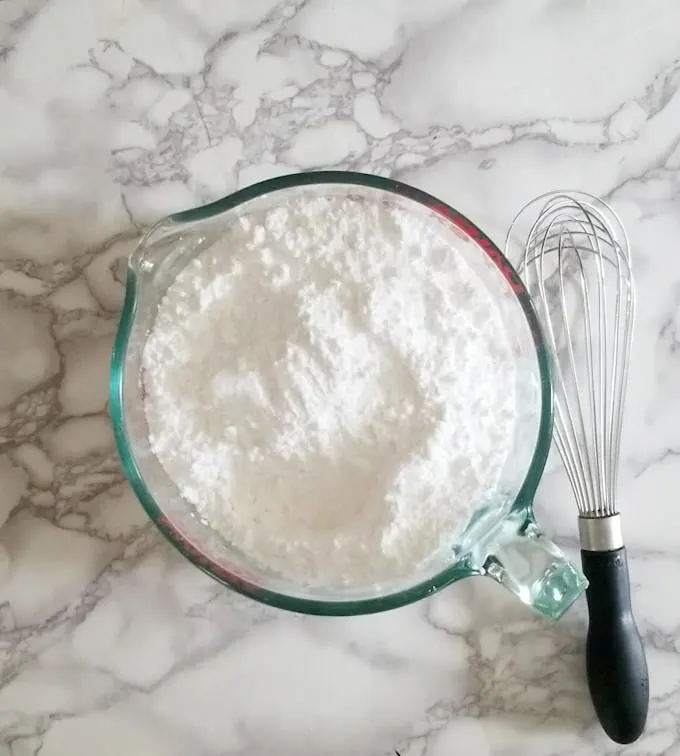 a bowl of powdered sugar and a whisk