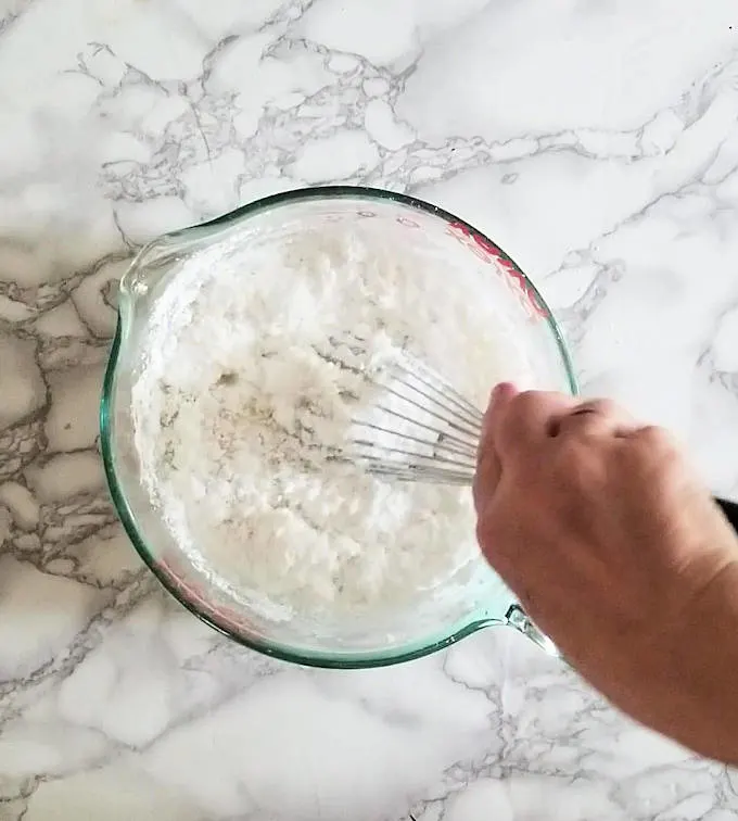whisking powdered sugar and syrup to make easy fondant icing