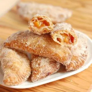 A plate of fried peach hand pies with one open at the top