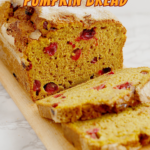 a sliced loaf of sourdough discard pumpkin bread on a wood cutting board.
